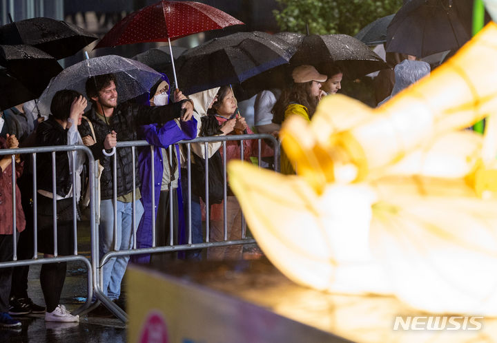 [서울=뉴시스] 김명년 기자 = 부처님오신날을 앞둔 11일 오후 서울 종로 일대에서 우산을 쓴 관람객들이 연등 행렬을 구경하고 있다. 2024.05.11. kmn@newsis.com