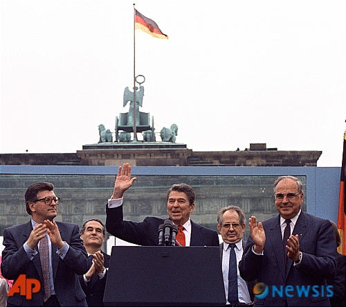 【베를린=AP/뉴시스】1987년 6월 12일 독일 베를린에서 헬무트 콜 당시 독일 총리(오른쪽)이 로널드 레이건 당시 미국 대통령이 연설하는 옆에 서서 박수치고 있다. 