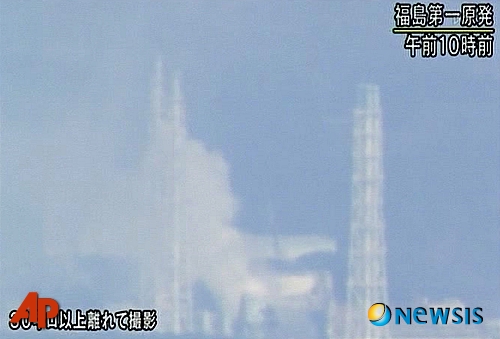 【오쿠마마치(일본)=AP/뉴시스】일본 동북부 강진 엿새째인 16일 아침 NHK 방송은 후쿠시마현 오쿠마마치의 후쿠시마 다이이치 원전에서 하얀 연기가 치솟는 모습을 방영했다.  NHK 방송은 자세한 사항은 촬영시간 현재까지 알려진 바 없다고 밝혔으며 화면 하단에는 이 영상이 30km 밖에서 촬영된 것이라 밝히고 있다.