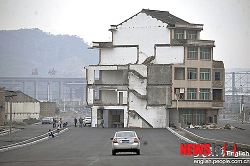 【서울=뉴시스】중국 저장(浙江)성 원링(溫嶺)시에 있는 기차역으로 향하는 고속도로에 5층짜리 아파트가 서 있다. 노부부는 정부의 이주 보상안에 불만이 있어 이사하지 않고 계속 살고 있다고 중국 인민일보(人民日報)가 22일(현지시간) 보도했다. 도로가 정식으로 개통되지 않았지만, 차량은 이 도로를 지나갈 때 이 집을 돌아가야 한다고 이 신문은 전했다. (사진 출처: 인민일보 인터넷판) 