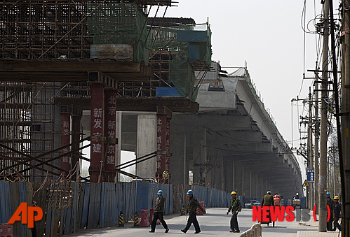 【베이징=AP/뉴시스】15일 중국 베이징의 건설 중인 고가도로 밑으로 몇 명의 노동자가 한가하게 지나가고 있다. 이날 중국 국가통계국은 올 1분기 국내총생산(GDP) 성장률이 작년 4분기의 7.9％에 비해 0.2％ 포인트 떨어진 7.7％를 기록했다고 발표했고, 기대에 못 미치는 경제 성장률 발표로 경기 회복세 둔화의 불안이 커졌다. 