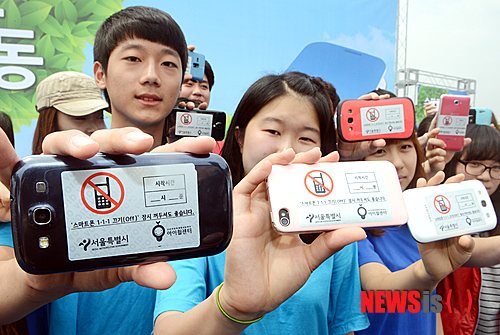 【서울=뉴시스】조성봉 기자= 23일 오전 서울 마포구 서울월드컵공원 평화의 광장에서 서울시 주최로 열린 스마트폰중독 예방을 위한 캠페인에 참석한 청소년들이 스마트폰끄기 스티커를 폰에 부착하고 '스마트폰 1-1-1 캠페인'을 홍보하고 있다. '스마트폰 1-1-1 캠페인'은 일주일에 한번 한 시간씩 스마트폰을 끄자는 제안이다. 2013.06.23. suncho21@newsis.com