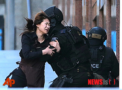 【시드니=AP/뉴시스】15일 시드니 카페에서 무장괴한에 인질로 붙잡혀 있던 여성이 탈출한 이후 경찰에 달려가고 있다. 2014.12.16