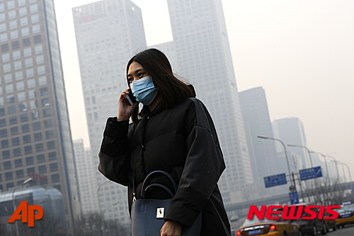 【베이징=AP/뉴시스】지난 2015년 12월7일 대기오염으로 짙은 연무가 낀 베이징 거리에서 한 여성이 마스크를 끼고 걷고 있다. 대기 오염이 여성들의 난소 활동을 저하시킨다는 연구 결과가 나왔다고 영국 가디언이 25일(현지시간) 보도했다. 2019.6.26 