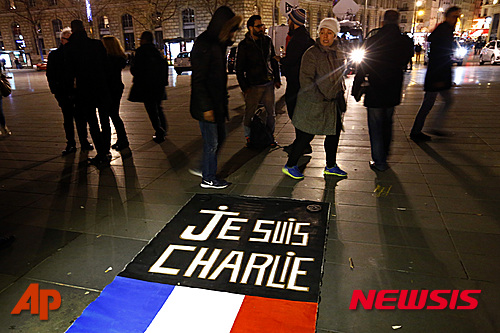 【 파리=AP/뉴시스】프랑스 파리의 '공화국 광장'에서 7일(현지시간) 시민들이 만평주간지 샤를리 에브도 테러 1주년을 맞아 추모 행사에 참여하고 있다. 길 바닥에 '나는 샤를리다'란 글자가 프랑스 국기와 함께 씌여있다. 2016.01.08  