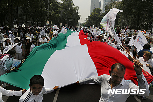【멕시코시티=AP/뉴시스】멕시코 수도 멕시코시티에서 24일(현지시간) '가족을 위한 국민전선'이 조직한 전국적인 동성결혼 합법화 반대시위에 21만여 명이 참가해 거대한 멕시코 국기를 들고가는 깃발 행진을 하고 있다. 엔리케 페냐 니에토 대통령이 동성결혼 합법화를 추진하는데 반대하는 이들과 찬성하는 소규모 시위대 사이에 수백 명의 경찰이 바리케이드를 치고 충돌을 막았다. 2016.09.25  . 