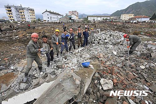 【 온성=AP/뉴시스】북한 함경북도 온성군 주민들이 지난 16일 홍수 피해 지역에서 부서진 건물의 시멘트 조각들을 옮기는 작업을 하고 있다. 2016.09.28