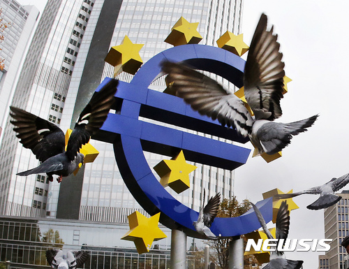 Pigeons fly in front of the Euro sculpture at the old European Central Bank bulding in Frankfurt, Germany, Thursday, Nov. 10, 2016. (AP Photo/Michael Probst)