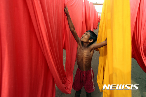 【AP/뉴시스】2012년 12월 자료 사진으로, 방글라데시 수도 교외에서 한 소년이 의복 염색 공장에서 일하고 있다.  2016. 12. 7.