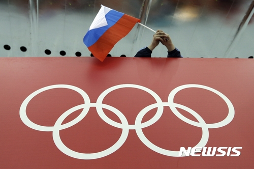FILE - In this Feb. 18, 2014 file photo, a Russian skating fan holds the country's national flag over the Olympic rings before the start of the men's 10,000-meter speedskating race at Adler Arena Skating Center during the 2014 Winter Olympics in Sochi, Russia. The Olympic world is bracing for more evidence of systematic Russian doping. World Anti-Doping Agency investigator Richard McLaren is releasing his latest report on Friday Dec. 9, 2016 into allegations of state-sponsored cheating and cover-ups in Russia. (AP Photo/David J. Phillip, file)