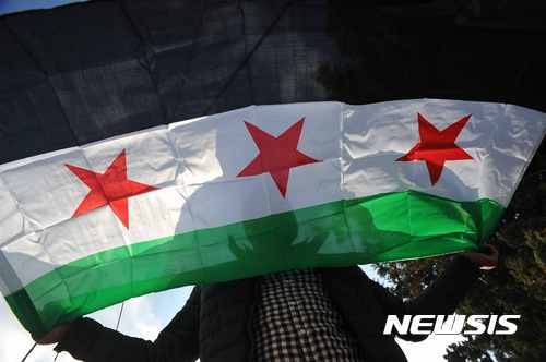 【암만(요르단)=뉴시스】 채정병 기자 = 17일(현지시간) 러-시리아 정부군의 시리아 알레포 공격을 규탄하고 민간인 학살 중단을 위한 유엔의 즉각적 개입을 촉구하는 시위가 UNDP(유엔개발계획) 암만 사무소 앞에서 열린 가운데 한 남성이 자유시리아군 기를 펼치고 있다.  청년들이 주축이 된 시위대는 민간인 사상자가 속출하는 알레포 사태를 소극적으로 대처하는 유엔을 비난하고 테러리스트를 축출한다는 명목으로 민간인을 학살하는 알 아사드 시리아 정부를 강력히 규탄했다. 2016.12.18. chae0191@newsis.com
