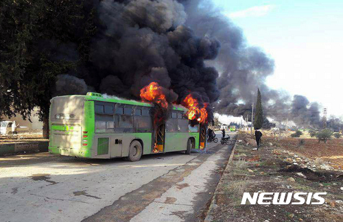 【이들리브=AP/뉴시스】시리아 알레포 인근 이들리브주에서 18일(현지시간) 알레포 주민 수송 버스가 괴한들의 공격을 받은 후 불길과 연기를 내뿜고 있다. 2016.12.19 