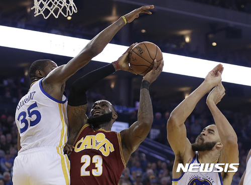Cleveland Cavaliers' LeBron James, center, shoots between Golden State Warriors' Kevin Durant (35) and JaVale McGee, right, during the first half of an NBA basketball game Monday, Jan. 16, 2017, in Oakland, Calif. (AP Photo/Ben Margot)