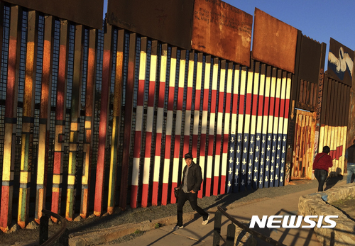 【티후아나=AP/뉴시스】멕시코 주민들이 25일(현지시간) 북서부 티후아나에 세워진 국경장벽을 따라 걸어가고 있다. 도널드 트럼프 미국 대통령이 이날 멕시코 국경 지역에 장벽을 설치하는 내용의 행정명력에 서명하자 엔리케 페냐 니에토 멕시코 대통령은 현지 TV 방송 연설에서 멕시코 국경 장벽 건설 행정명령에 대해 유감을 표하고 비용 부담을 거부했다. 2017.01.26   