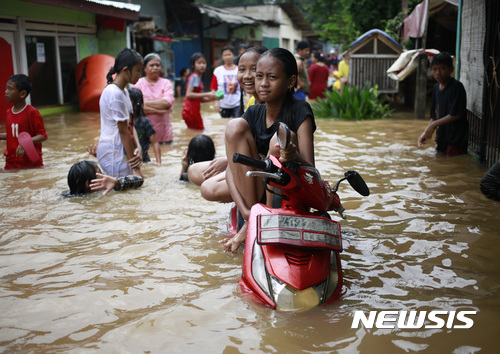【 자카르타=AP/뉴시스】인도네시아 수도 자카르타에서 21일 홍수가 발생한 가운데 소녀 두 명이 스쿠터에 올라 앉아 있다. 2017.02.21 