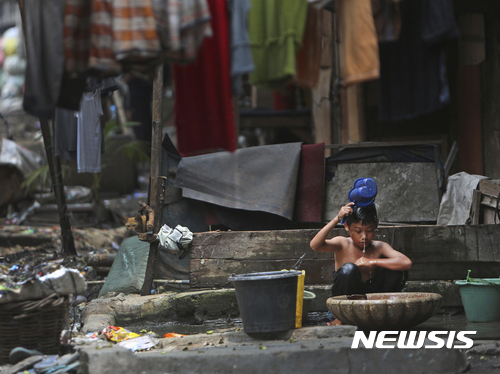 【자카르타=AP/뉴시스】인도네시아 자카르타의 한 빈민촌에서 바가지로 물을 떠서 몸을 씻고 있는 어린이의 모습. 국제 구호기구 옥스팜은 23일 발표한 보고서에서 인도네시아 최고 부호 4명이 하위 1억명의 부를 독점하고 있다고 지적했다. 2017.02.23  