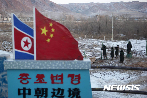 FILE - In this Dec. 8, 2012, file photo, Chinese paramilitary policemen build a fence near a concrete marker depicting the North Korean and Chinese national flags with the words "China North Korea Border" at a crossing in the Chinese border town of Tumen in eastern China's Jilin province. China’s announcement it has suspended North Korean coal imports may have been its first test of whether the Trump administration is ready to do something about a major, and mutual, security problem: North Korea’s nukes. While China is Pyongyang’s biggest enabler, it is also the biggest outside agent of regime-challenging change - just not in the way Washington has wanted. (AP Photo/Ng Han Guan, File)