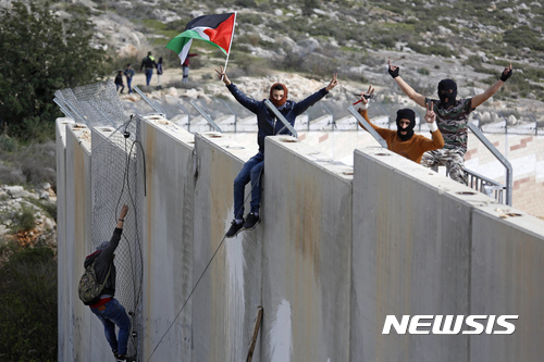 【라말라=AP/뉴시스】지난해 3월 팔레스타인 시위자들이 이스라엘과 서안 지구를 가르는 분계 장벽에 올라 장벽 항의 12돌을 기리는 시위를 하고 있다. 2017. 3. 7.