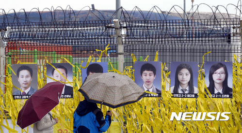 【목포=뉴시스】류형근 기자 = 인양된 세월호 육상거치를 앞둔 5일 오전 전남 목포시 목포신항에서 추모객들이 철망에 걸려 있는 미수습자 9명의 사진을 보고 있다. 2017.04.05. hgryu77@newsis.com