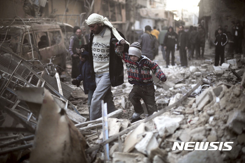 【구타=AP/뉴시스】6년째 장기화된 내전으로 황폐화된 시리아의 모습. 2015년 12월 24일 구타에 사는 한 부자가 공습 이후 무너져 내린 건물 잔해를 지나가고 있다. 2017.4.17.