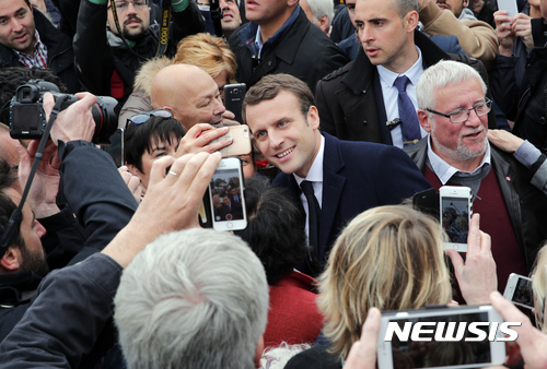 Centrist candidate Emmanuel Macron poses as he leaves after casting his vote in the first round of the French presidential election, in le Touquet, northern France, Sunday April 23, 2017. (AP Photo/Christophe Ena)