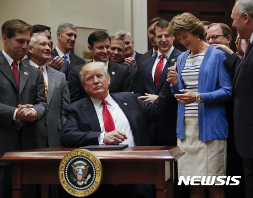 President Donald Trump, gives the pen he used to sign an Executive Order to Sen. Lisa Murkowski, R-Alaska, right, in the Roosevelt Room of the White House in Washington, Friday, April 28, 2017. The Executive Order directs the Interior Department to begin review of restrictive drilling policies for the outer-continental shelf. (AP Photo/Pablo Martinez Monsivais)