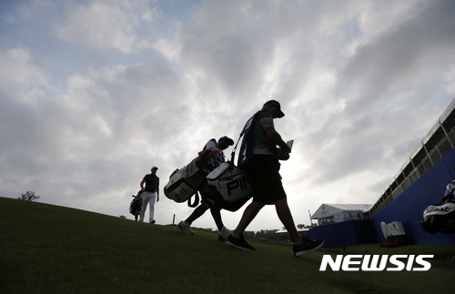 Caddies and golfers walk off the ninth green under darkening skies, during the second round of the PGA Zurich Classic golf tournament's new two-man team format at TPC Louisiana in Avondale, La., Friday, April 28, 2017. (AP Photo/Gerald Herbert)