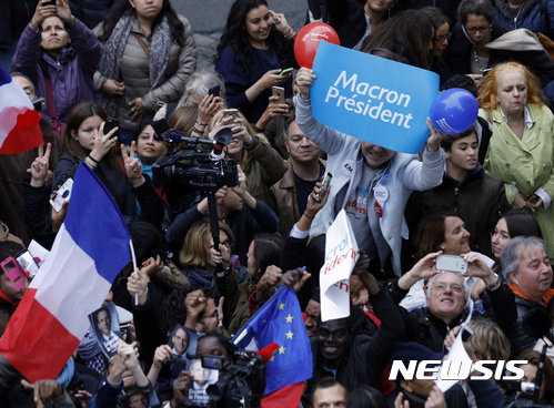 【파리=AP/뉴시스】7일(현지시간)치러진 프랑스 대통령선거에서 에마뉘엘 마크롱이 승리하자 파리 시민들이 '마크롱 대통령'이라고 쓴 종이를 들어보이며 기뻐하고 있다. 2017.05.08 