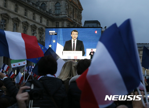 Emmanuel Macron's supporters watch the president-elect speaking on a giant screen at the Louvre museum where Emmanuel Macron is planning to celebrate, Sunday, May 7, 2017 in Paris. Ripping up France's political map, French voters elected centrist Emmanuel Macron as the country's youngest president ever Sunday, delivering a resounding victory to the unabashedly pro-European former investment banker and strengthening France's place as a central pillar of the European Union. (AP Photo/Francois Mori)