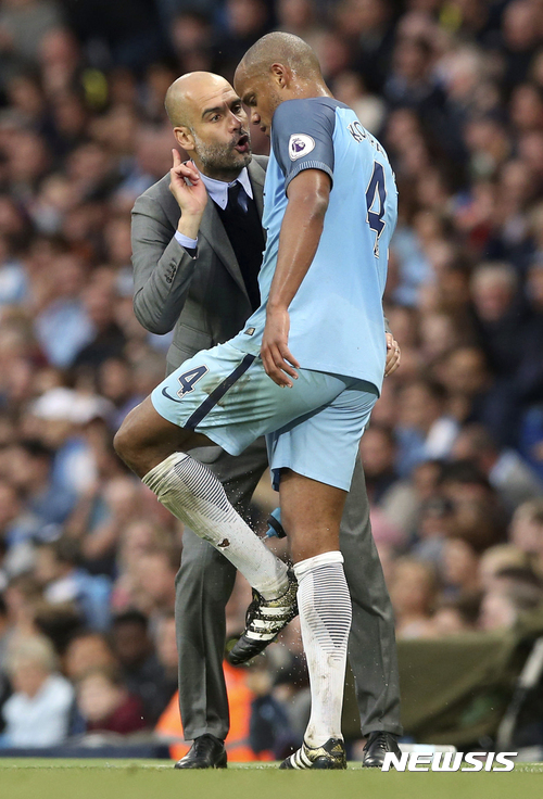 Manchester City manager Pep Guardiola, left, talks with player Vincent Kompany during the English Premier League soccer match against West Bromwich Albion at the Etihad Stadium, Manchester, England, Tuesday May 16, 2017. (Martin Rickett/PA via AP)