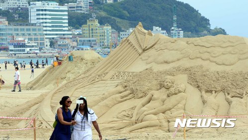 【부산=뉴시스】 하경민 기자 = 지난 21일 부산 해운대해수욕장 백사장에 더위를 식히러 나온 시민들과 관광객들이 모래조각 작품을 감상하며 지나가고 있다.  2017.05.21. yulnetphoto@newsis.com