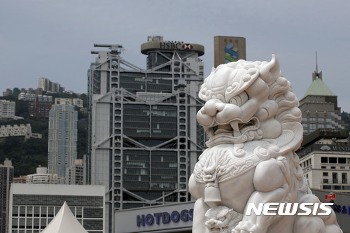 A lion statue sits in Hong Kong's business district of Central with financial buildings in rear, Thursday, May 25, 2017. Moody's has cut its credit rating for Hong Kong hours after downgrading China for rising debt levels, which it said would have "significant impact" on the Asian financial hub because of their close links. (AP Photo/Kin Cheung)