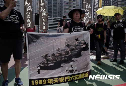【홍콩=AP/뉴시스】28일 홍콩 도심에서 중국 톈안먼사태(6.4 민주화 운동) 28주기 기념 추모 행진이 열린 가운데 한 시위자가 '탱크맨' 사진이 인쇄된 플래카드를 들고 있다. 이날 행진에 약 1000명이 참석했는데 이는 연례 거리행진 최소 규모로 알려졌다. 2017.05.29 