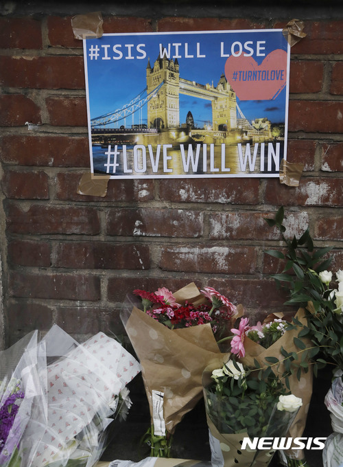 【런던=AP/뉴시스】 4일(현지시간) 영국 런던브리지에 테러 희생자들을 추모하는 꽃다발이 놓여있다. 벽에는 '사랑이 테러리즘을 이긴다'는 의미의 문구가 적힌 포스터가 붙어있다. 2017.6.5.