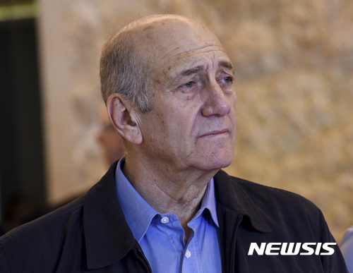 FILE -- In this Dec. 29, 2015 file photo, former Israeli Prime Minister Ehud Olmert leaves the courtroom of the Supreme Court after the court ruled on his appeal in the Holyland corruption case in Jerusalem. The parole board of Israel's Prison Service on Thursday granted former Prime Minister Ehud Olmert early release from his 27-month corruption sentence. Barring any unforeseen developments, Olmert will walk free on Sunday, July 2, 2017. (Debbie Hill/Pool File Photo via AP)