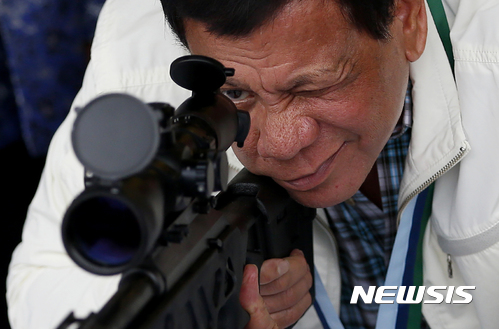 【클라크공군기지=AP/뉴시스】로드리고 두테르테 필리핀 대통령이 6월28일 북부 클라크 공군기지에서 중국으로부터 대량으로 수입한 무기 중 라이플 총을 겨뤄보고 있다. 두테르테는 30일로 대통령 취임 1년을 맞았다. 2017.06.30 