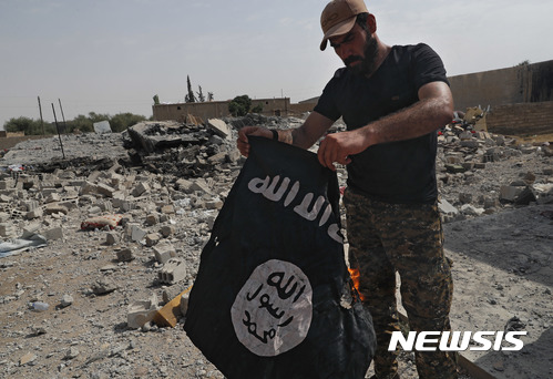 【락까(시리아)=AP/뉴시스】미국의 지원을 받는 시리아반군 시리아민주군(SDF) 대원 1명이 17일 시리아 이슬람국가(IS) 수도인 락까에서 IS 깃발을 불태우고 있다. 2017.7.18