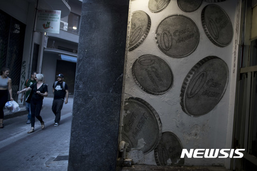  【아테네(그리스) =AP/뉴시스】 = 경제위기 속에서도 꾸준한 노력으로 최근 회복세를 보이고 있는 그리스에서 아테네시내의  동전 벽화 앞을 보행자들이 지나가고 있다.  