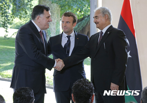 【파리=AP/뉴시스】리비아의 파예즈 사라지 총리(왼쪽), 칼리파 하프타르 리비아 국군 사령관(오른족)이 25일(현지시간) 파리에서 에마뉘엘 마크롱 프랑스 대통령(가운데)의 중재 아래 휴전을 합의하고 악수하고 있다. 2017.7.26.