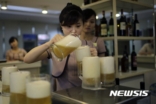 【평양=AP/뉴시스】북한 평양에서 26일 여 종업원이 대동강 맥주 신제품을 따르고 있다. AP통신은 북한 대동강 맥주는 일반적으로 세계적 수준으로 평가받고 있으며, 많은 북한인들이 국가적 자랑으로 여기고 있다고 전했다. 2017.07.27