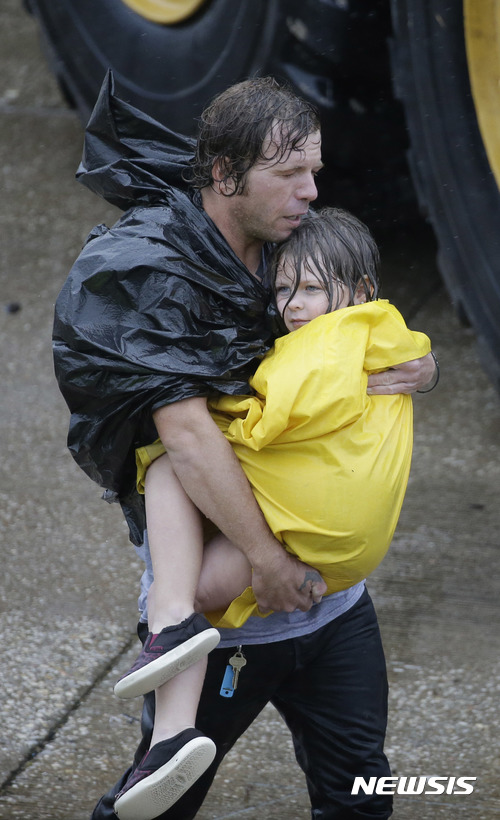 【휴스턴=AP/뉴시스】허리케인 하비의 영향으로 폭우가 내려 대홍수가 발생한 미국 텍사스주 휴스턴에서 28일(현지시간) 한 남성이 비에 젖은 아이를 안고 걸어가고 있다. 2017.08.29 