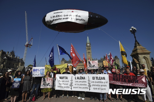 【오타와( 캐나다) = AP/뉴시스】 = 22일(현지시간) 북미자유협정(NAFTA)에 반대하는 시위대가 캐나다의 오타와 국회의사당 앞에 모여서 소형 비행선을 띄워놓고 나프타 재협상에 반대하는 집회를 열고 있다.  
