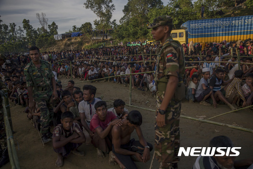 【발루칼리 난민수용소(방글라데시)=AP/뉴시스】방글라데시 군인들이 25일 방글라데시의 발루칼리 난민수용소에서 지원 물품을 배분받기 위해 줄지어 기다리는 미얀마 로힝야족 무슬림 난민들의 질서를 유지하기 위해 지키고 있다. 미얀마 정부는 이날 북부 라카인주에서 힌두교도 17명이 묻힌 집단 매장지 1곳이 추가 발견돼 지금까지 숨진 힌두교도 숫자가 45명으로 증가했다며 이들은 로힝야 반군에 의해 살해된 것이라고 비난했다. 2017.09.26