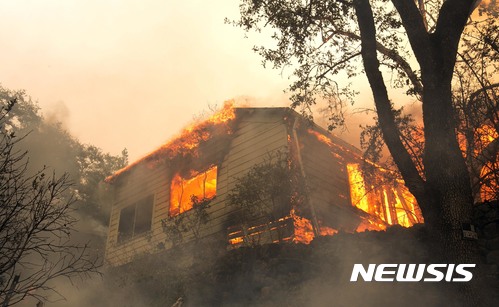 【내파 (미 캘리포니아주) = AP/뉴시스】 = 캘리포니아주 내파 동쪽의 실베라도 트레일에 있는 한 주택이 9일(현지시간) 강풍을 타고 번진 산불로 불타고 있다.   