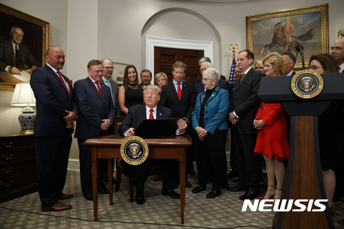 【워싱턴=AP/뉴시스】 도널드 트럼프(가운데) 미국 대통령은 12일(현지시간) 백악관에서 중소기업인들과 공화당원들이 모인 가운데 오바마케어에서 규제하고 있는 건강보험 조항을 폐기하는 행정명령에 서명하고 입장을 밝히고 있다. 2017.10.13.