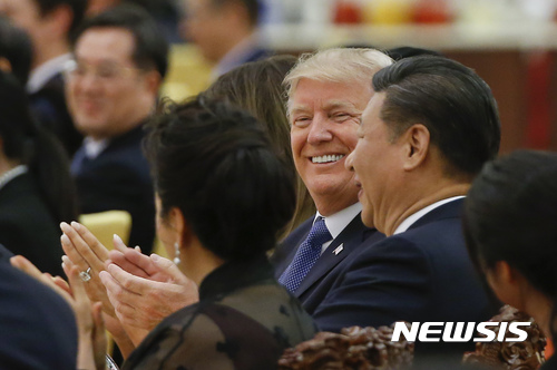 【베이징=AP/뉴시스】 도널드 트럼프 미 대통령과 시진핑 중국 주석이 9일 인민대회당 국빈 만찬에서 나란히 앉아 웃고 박수하며 즐거워하고 있다. 시 주석 옆에 펑리위안 여사가 보이고 저쪽 트럼프 대통령 옆에 멜라니아 여사가 앉아 있다. 2017. 11. 9.