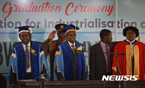 Zimbabwe's President Robert Mugabe, center, stands for the national anthem after arriving to preside over a student graduation ceremony at Zimbabwe Open University on the outskirts of Harare, Zimbabwe Friday, Nov. 17, 2017. Mugabe is making his first public appearance since the military put him under house arrest earlier this week. (AP Photo/Ben Curtis)