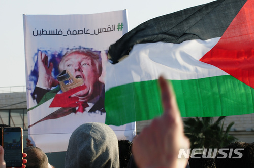 【암만(요르단)=뉴시스】 채정병 기자 = 13일(현지시간) 트럼프의 예루살렘 수도 인정에 분노한 요르단 무슬림들이 주 요르단 미국 대사관 앞에서 시위를 벌인 가운데 '예루살렘은 팔레스타인의 수도'라는 문구 아래 트럼프를 조롱하는 이미지를 들고 미국을 규탄하고 있다.  이들은 1994년에 맺은 이스라엘-요르단 간 평화협정 파기 및 대사관 철수를 촉구했다.  2017.12.14.chae0191@newsis.com