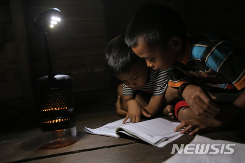 【서울=뉴시스】인도네시아 어린이들이 조명 소셜벤처 루미르가 개발한 '루미르K'의 빛을 이용해 책을 보고 있다. '루미르K'는 현지에서 쉽게 구할 수 있는 폐식용유를 활용해 빛을 내는 램프다. 2018.01.06. (사진=루미르 제공)