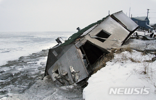 FILE - In this Dec. 8, 2006, file photo, Nathan Weyiouanna's abandoned house at the west end of Shishmaref, Alaska, sits on the beach after sliding off during a fall storm in 2005.  Alaska health officials are warning that serious health issues could crop up as the state warms. A report by the Alaska Division of Public Health released this week says longer growing seasons and fewer deaths from exposure are likely positive outcomes from climate change. But the 77-page report says additional diseases, lower air quality from more wildfires, melting permafrost and disturbances to local food sources also are potential outcomes. Warming already has thawed soil and eroded coastlines, leading at least three villages, Shishmaref, Kivalina and Newtok to consider relocating.  (AP Photo/Diana Haecker, File)